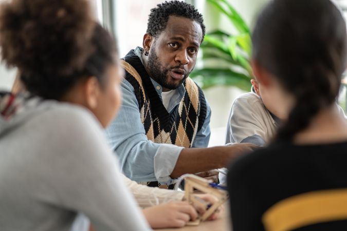 Male teacher speaking to teenager students around a table