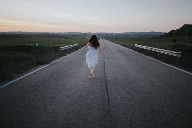 Anonymous woman running along countryside road