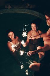 Cheerful friends burning sparkles near pool