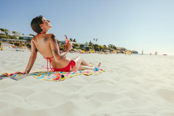 Tattooed woman closing her eyes and relaxing at the beach