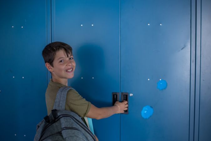 Teenager turning around smiling at his blue school locker