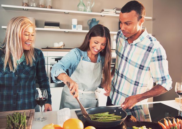 Multi-ethnic friends cooking asparagus on a pan