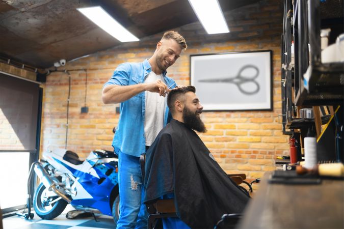 Male barber cutting bearded man’s hair