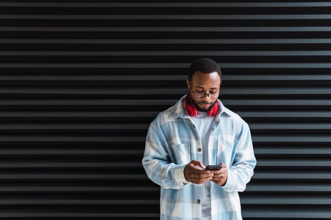 Cheerful Black man with smartphone listening to music