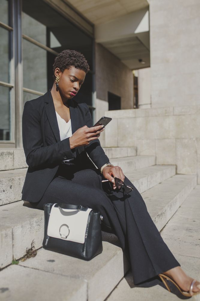Stylish black woman with handbag and sunglasses on steps