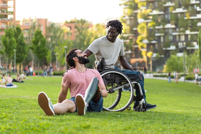 Man in wheelchair and man with prosthetic leg hang out together in park