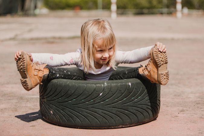 Little girl sitting inside tire