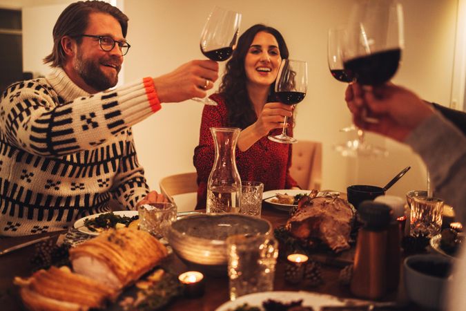 Family having a Christmas eve dinner together holding glasses up in cheers