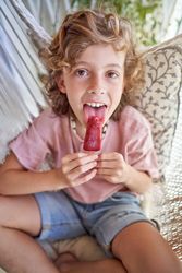 Cute child licking sweet ice lolly and looking at camera