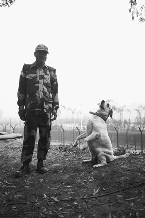 Black man in camouflage gear next to a dog sitting pretty on hind legs