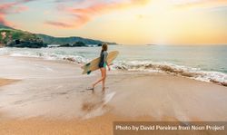 Woman standing on the shore with surfboard walking into the ocean 0Ja7nb