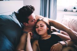 Young man kissing a young woman’s forehead tenderly