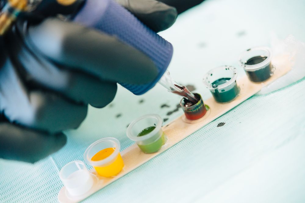 Tattoo artist’s hands loading up gun with mixed ink