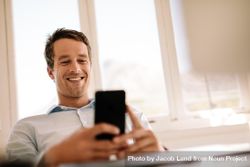 Low angle shot of male smiling at mobile phone 4Ozpj5