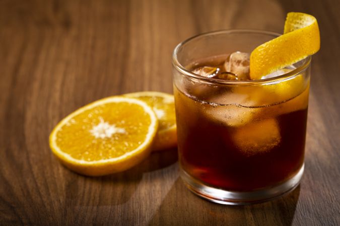 Negroni cocktail with orange, on wooden background.