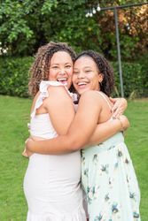 Hispanic mother and teenage daughter hug and smile at the camera