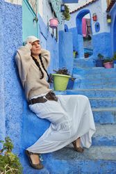 Pensive woman sitting on steps between ancient buildings