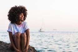 Delighted Black woman laughing at seaside
