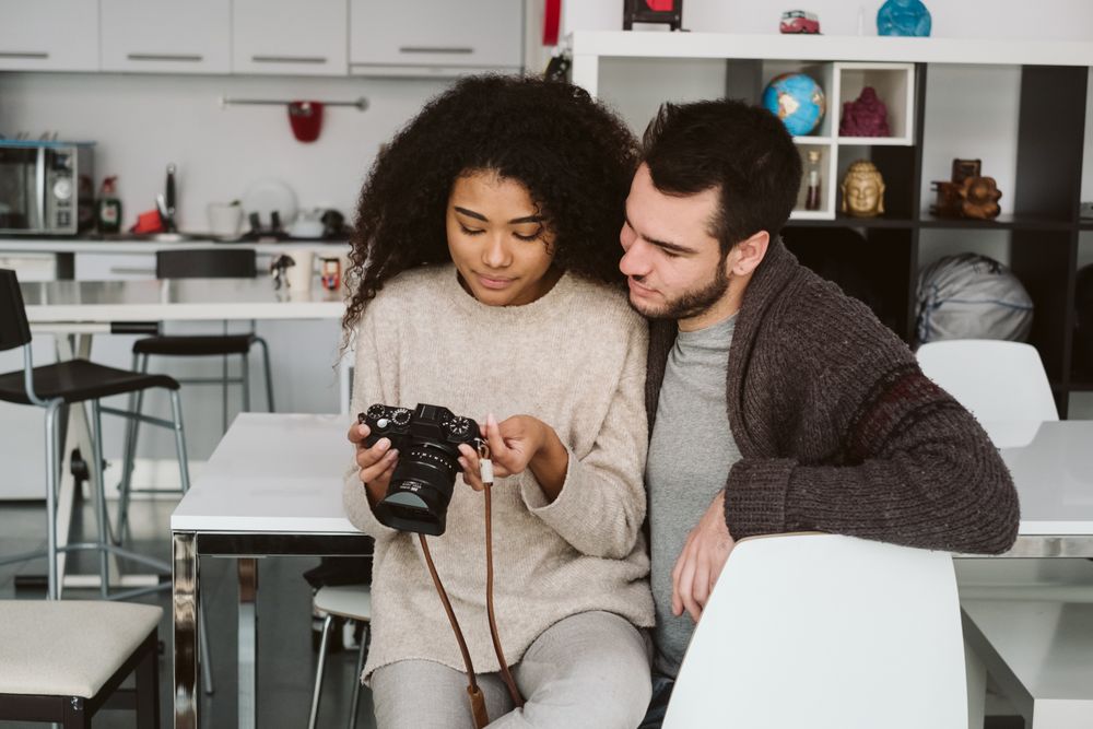 Multiracial couple looking at photo camera at home
