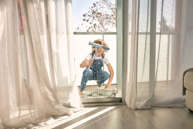 Anonymous kid cleaning windows at home