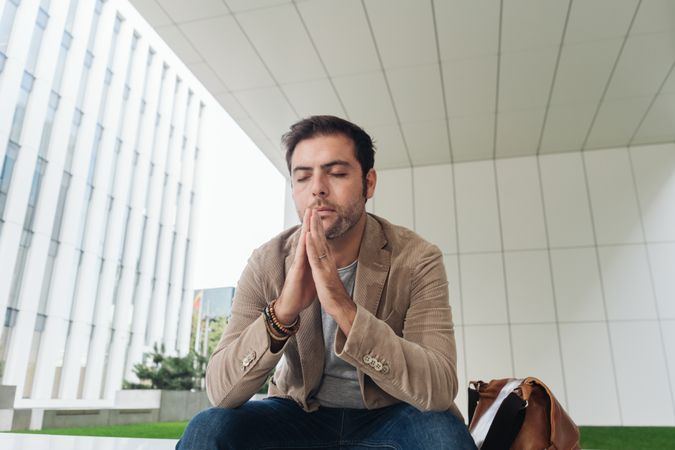 Thoughtful manager sitting outside modern building