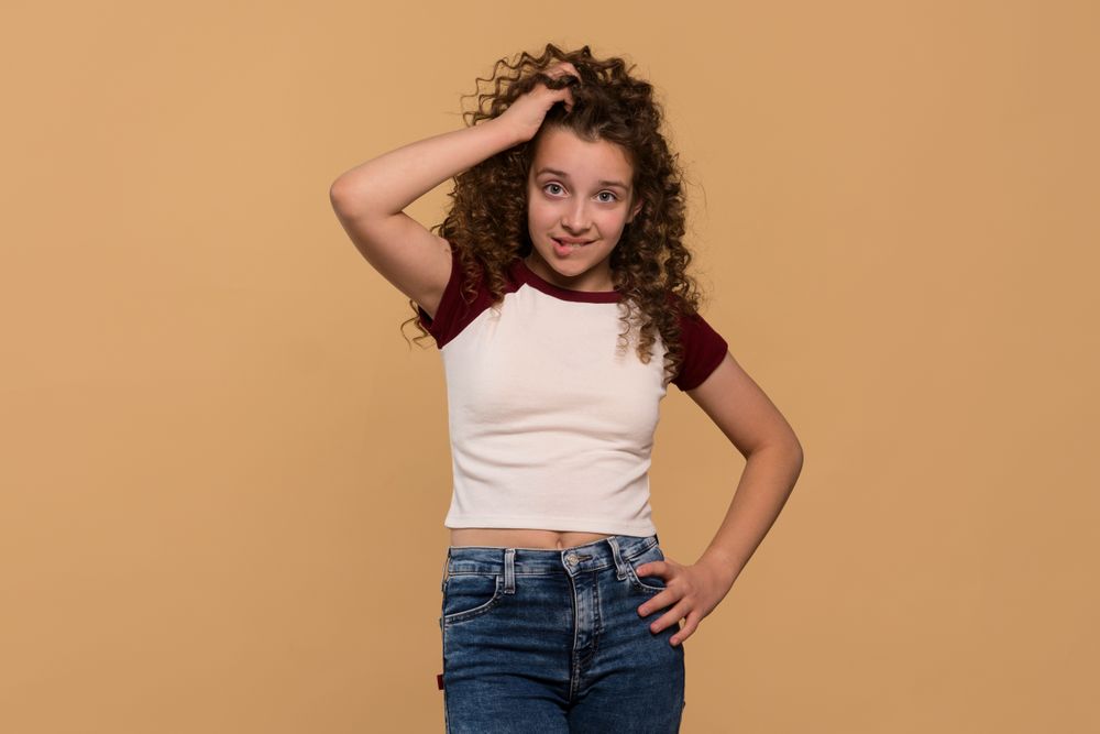 Young girl scratching head and biting lip, showing confusion