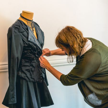 Fashion designer dressing a mannequin with dark clothes