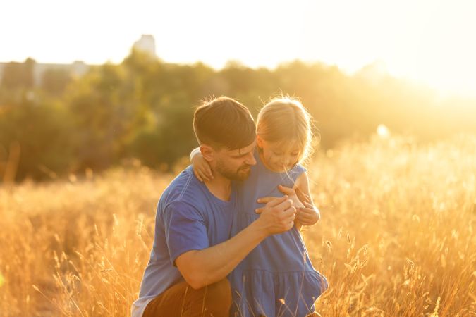 Dad and daughter sitting in field of long grass
