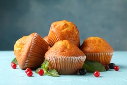 Composition with muffins and berries on blue background, close up