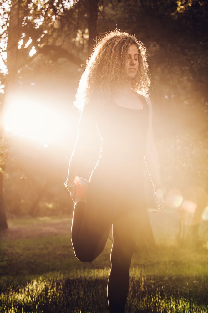 Sportive woman standing on meadow in sunlight