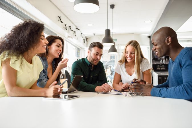 Group of people sharing a joke at a meeting around a table to go through work project