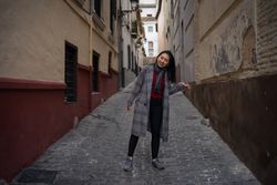Joyful Asian resting female hiking on old rocked narrow street