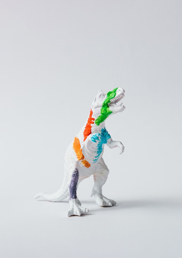 Plastic dinosaur splattered with different colors of paint