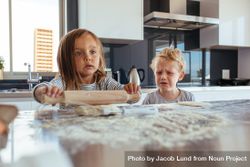 Cute little girl preparing a dough for cookies and little boy crying standing by 0VWJ35