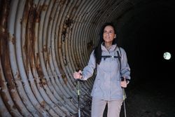 Hispanic hiker with poles in dark tunnel