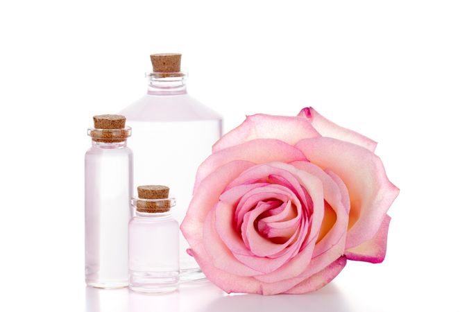 Three small glass bottles next to a rose