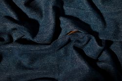 Close up detail crumpled wavy Navy blue jeans fabric background texture.
