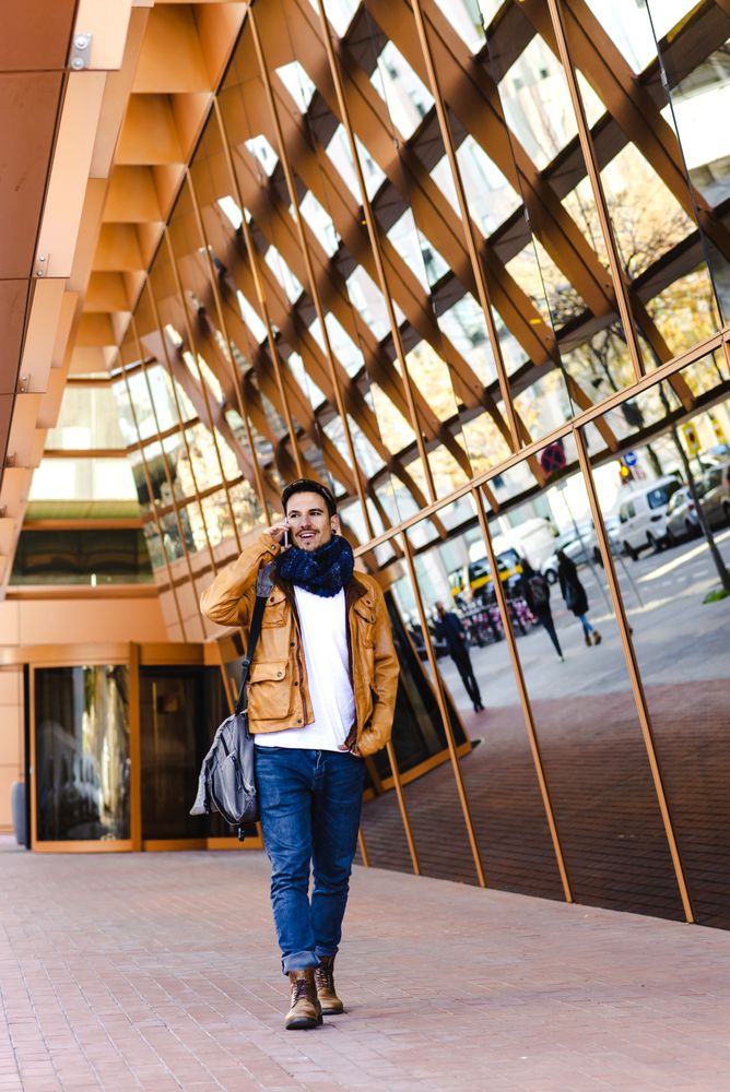 Stylish guy using smartphone outside modern building