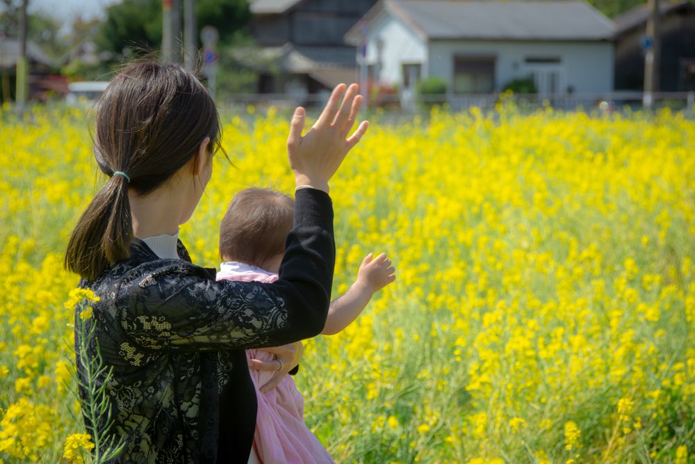 Back view of mother carrying her baby and waving