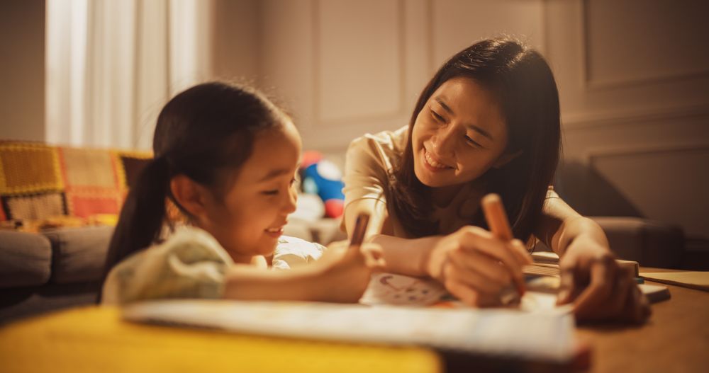 Portrait of a Korean Mother and her Cute Daughter Spending Evening Time Together in the Living Room at Home.