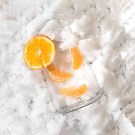 Glass with oranges on sliver icy background