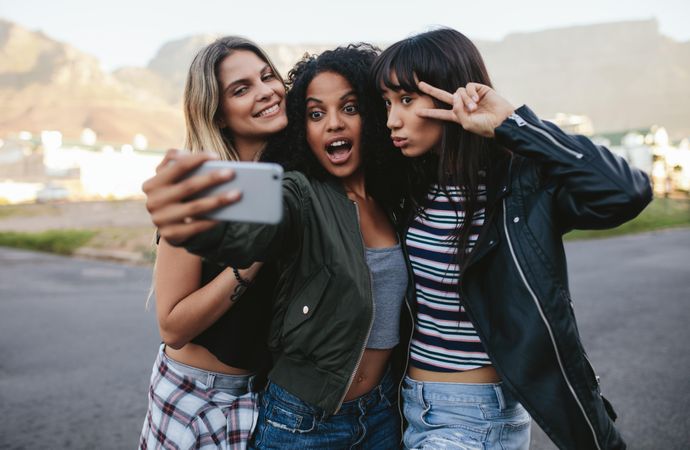 Female best friends posing and gesturing peace sign for selfie