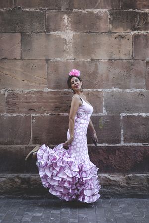 Passionate woman in flamenco dress dancing on street