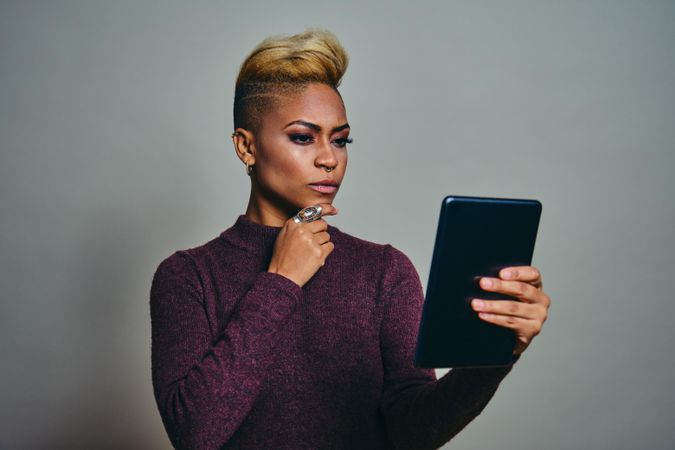Black woman contemplating something on a tablet