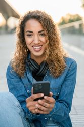Smiling woman with smartphone on street
