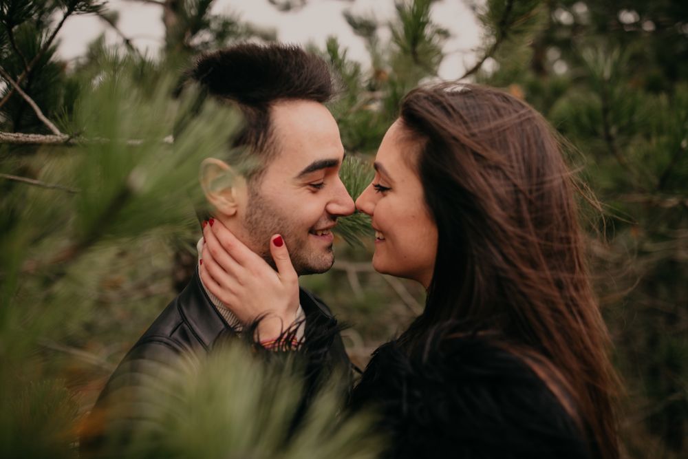 Happy couple hugging among pine forest