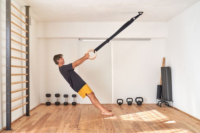 Sportsman exercising with gymnastic rings in gym