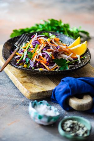 Fresh salad with finely chopped vegetables and lemon slices in bowl on counter with copy space