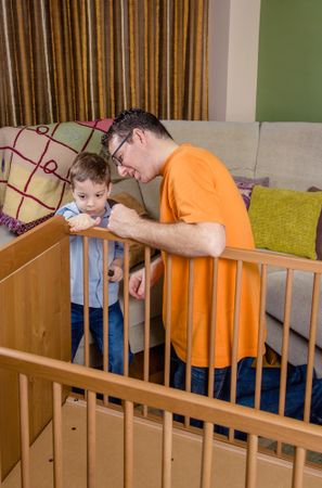 Father and son assembling cot for a newborn at home