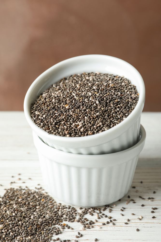 Ceramic sauce boats with chia on wooden background, copy space
